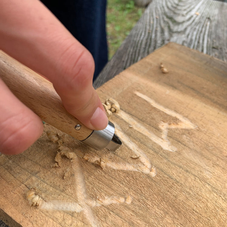 Hands whittling wood with the Kikkerland Huckleberry wood carving tool