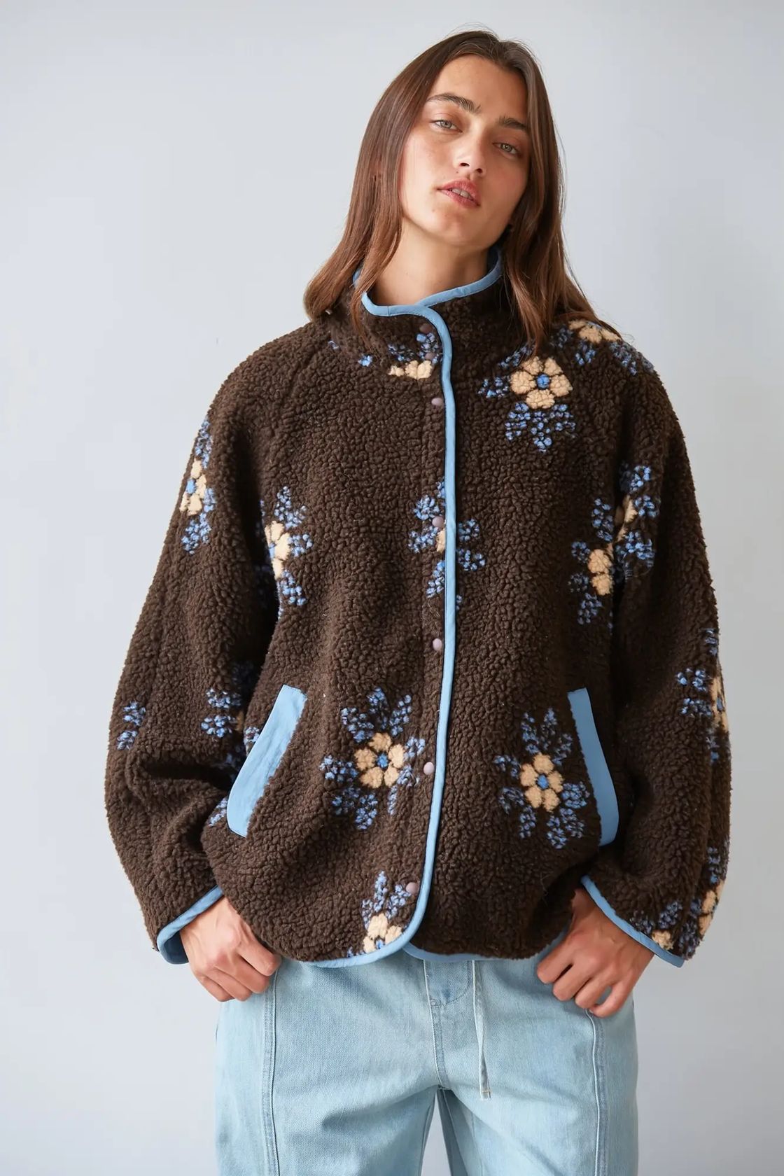 Woman wearing chocolate brown knit sherpa fleece jacket with light blue and cream floral print, mock neck and button front