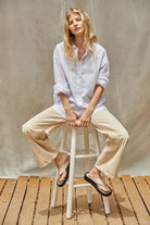 Light blue oversized woven cotton button-down shirt with a pointed collar and rolled long sleeves, styled with beige wide-leg pants
