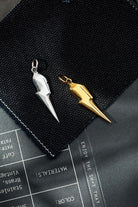 Silver and gold spike-shaped keychains on a black surface with text.