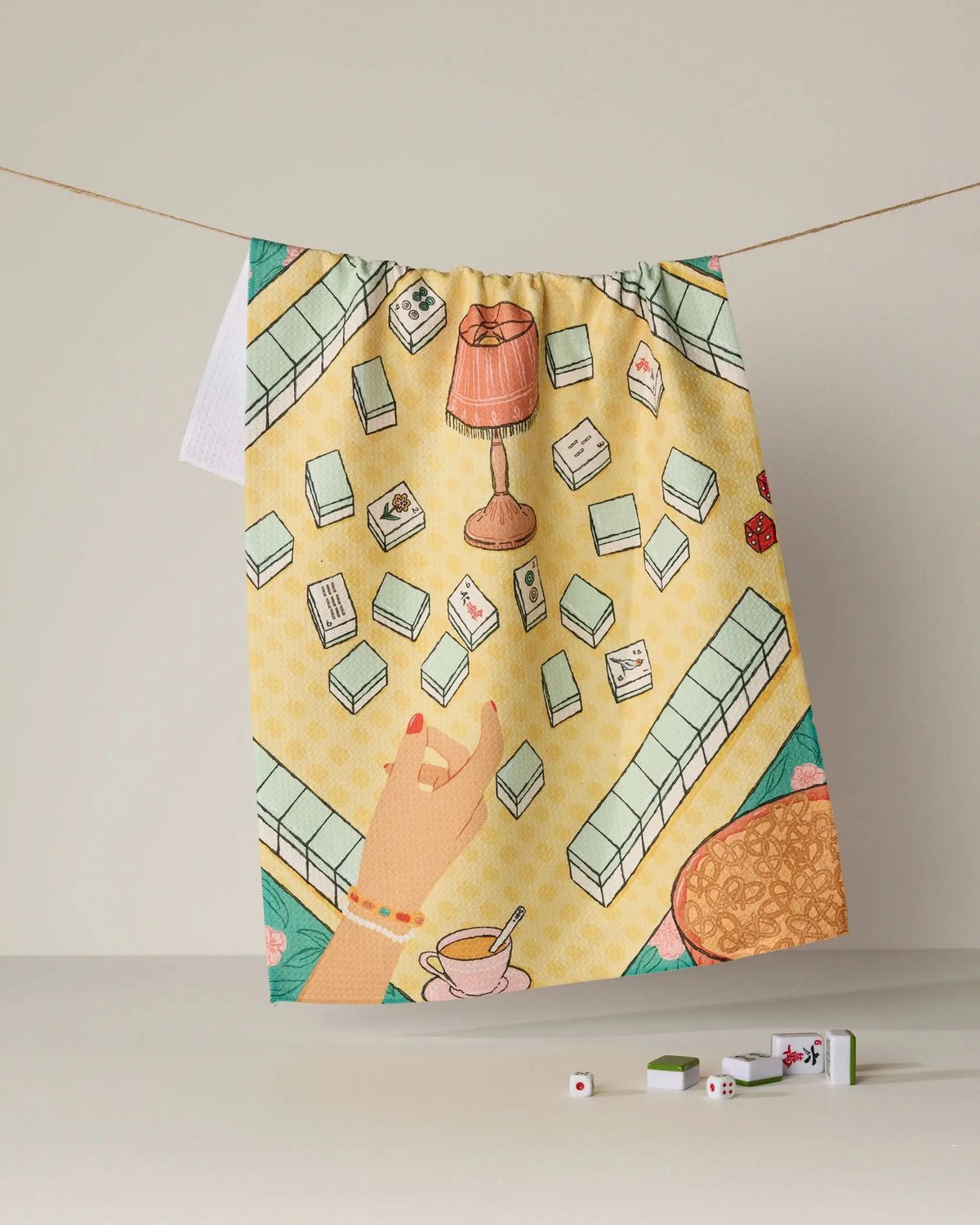 Lucky Hand mahjong tea towel in sunny yellow with illustrated mahjong tiles hanging on a line