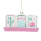 Hand-painted glass Christmas ornament of three white mahjong tiles on a pink glitter rack with a gold hanging loop
