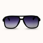 A pair of matte black aviator-style sunglasses with a gradient purple-to-silver lens, shown against a plain off-white background.
