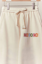 Close-up of the drawstring waist and small Ho Ho Ho detail on the cream sweatpants