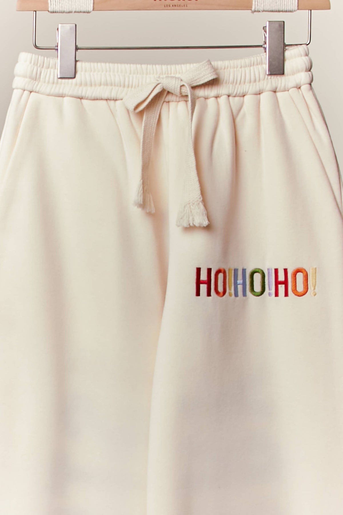 Close-up of the drawstring waist and small Ho Ho Ho detail on the cream sweatpants