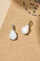 Two teardrop-shaped earrings on a beige background with text.