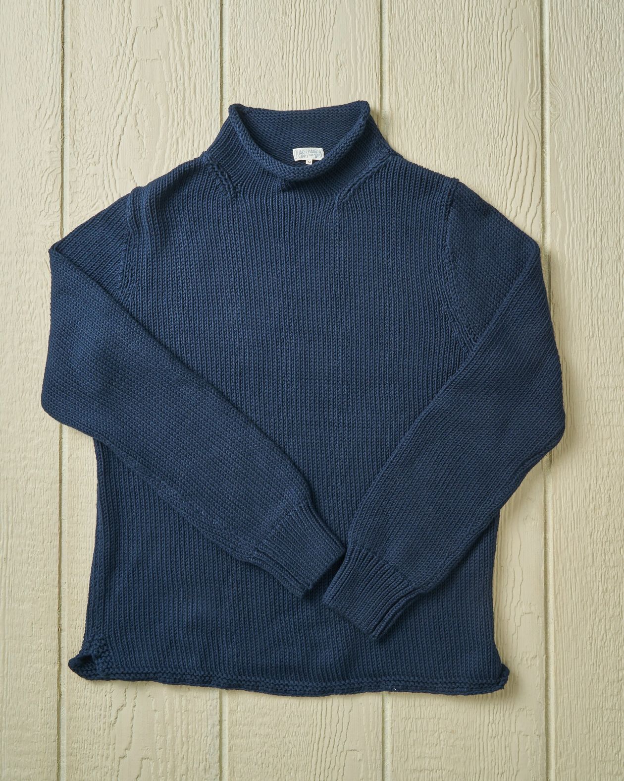 Blue rollneck sweater on a wooden surface