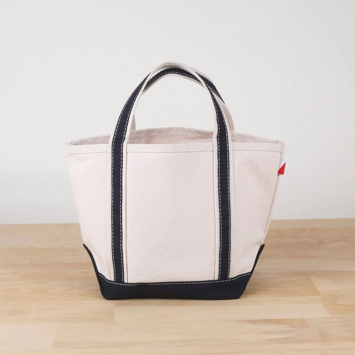 Beige tote bag with black accents on a wooden surface