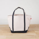 Beige tote bag with black accents on a wooden surface