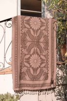 Patterned towel hanging on a railing with a blurred outdoor background
