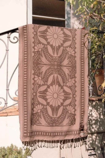 Patterned towel hanging on a railing with a blurred outdoor background