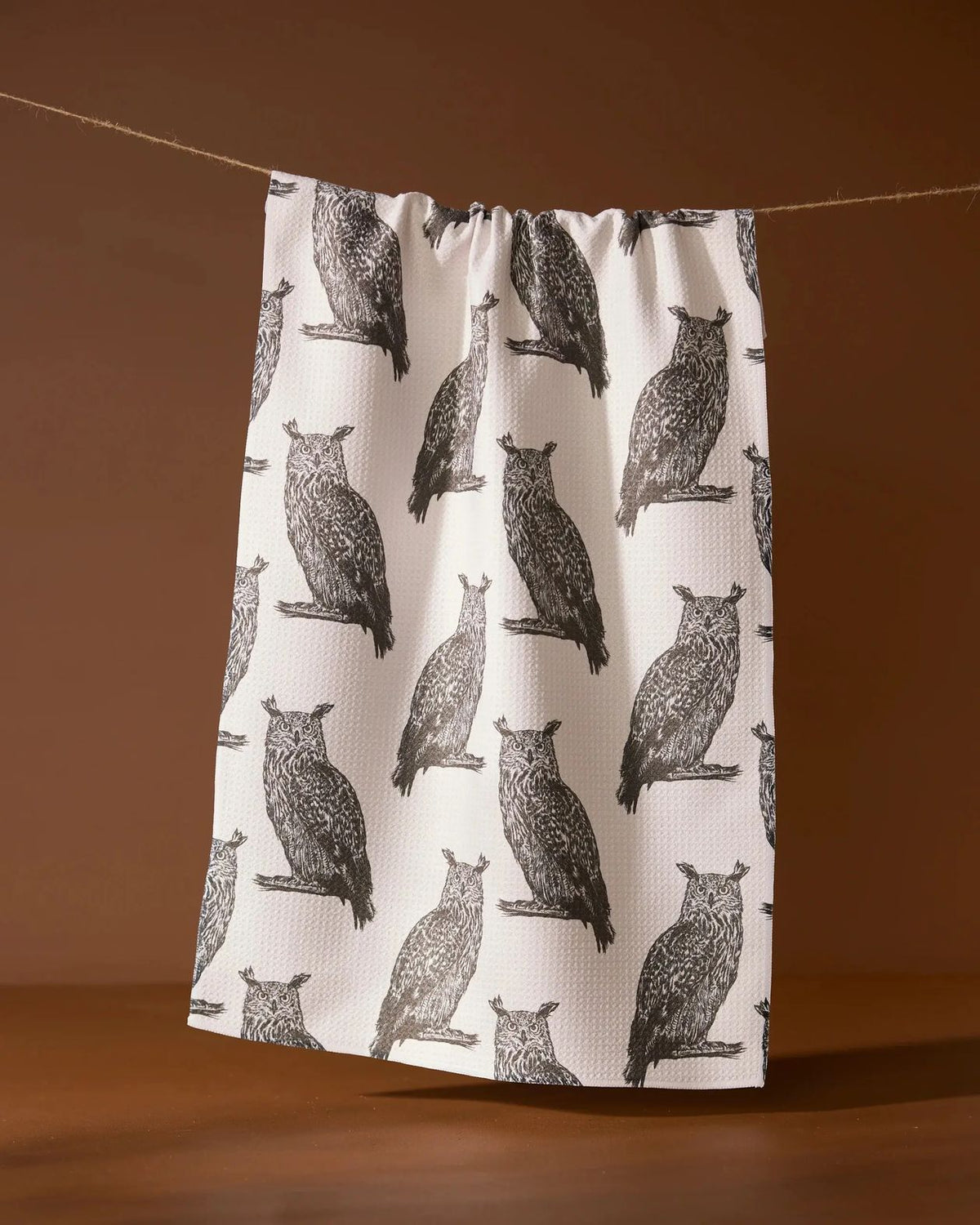 Nocturne tea towel in creamy white with gray owl print hanging on a line