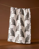 Nocturne tea towel in creamy white with gray owl print hanging on a line