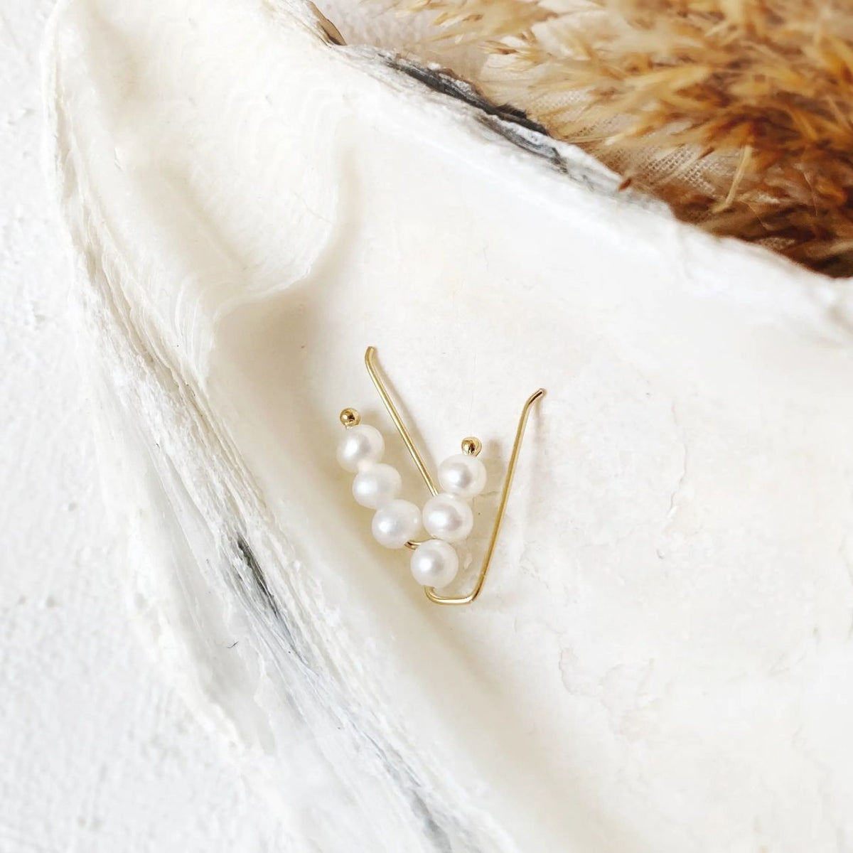 Gold earring with pearls on a white feather