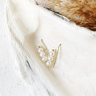 Gold earring with pearls on a white feather
