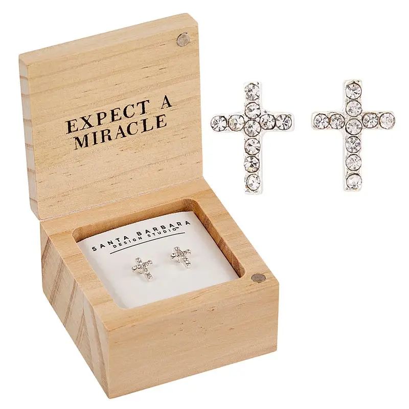 Wooden box with 'Expect a Miracle' text, containing cross-shaped earrings.