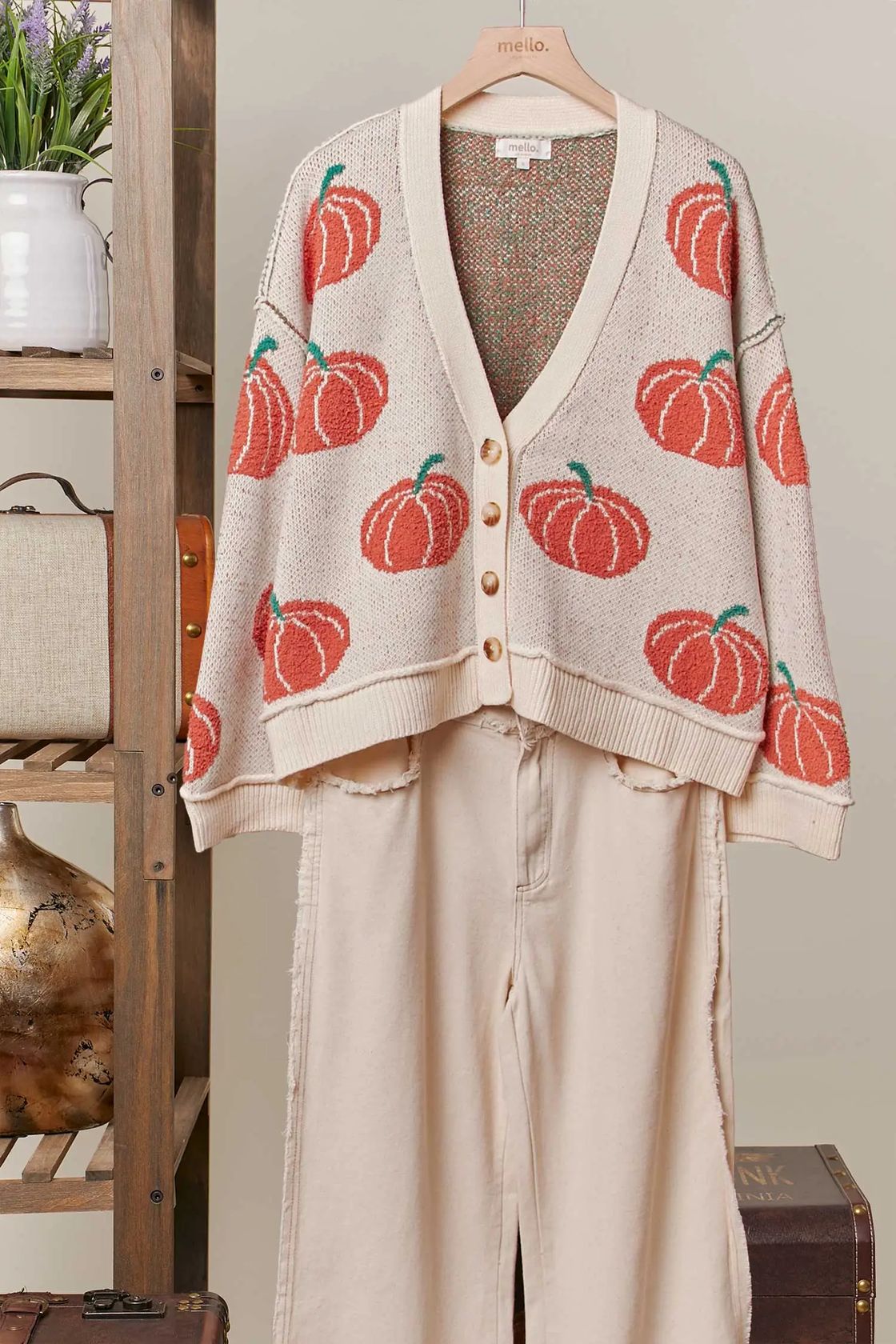 Cardigan with pumpkin pattern on a hanger against a neutral background