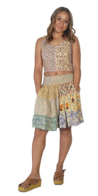Woman wearing a patterned sleeveless top and skirt on a white background