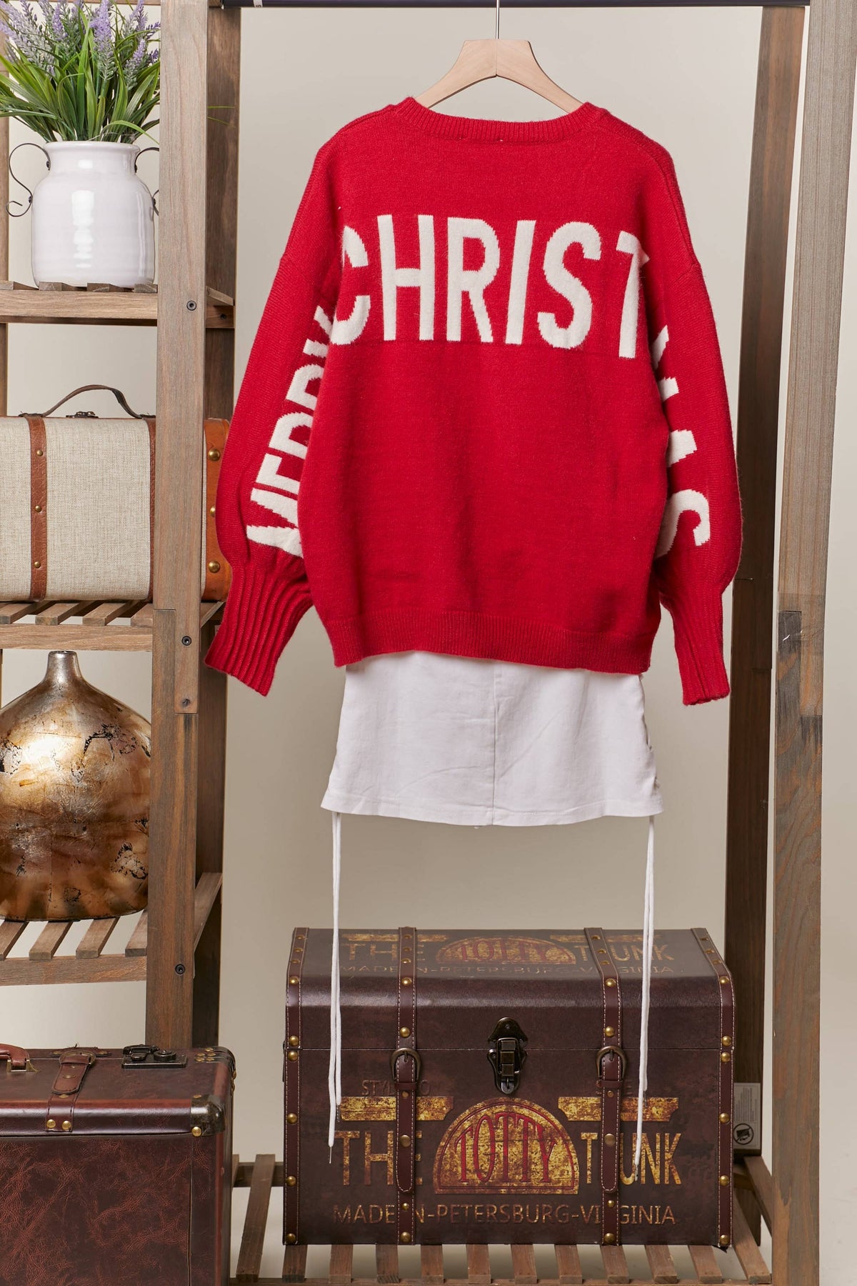 Back of the red sweater on a hanger showing ivory Merry Christmas lettering across the back and sleeves