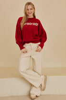 Model in the Red Merry Christmas Sweater and cream wide-leg pants, full-length view