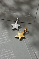 Gold and silver star-shaped pendants on a textured surface with 'Anchor' branding.