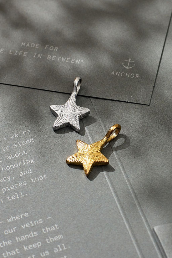 Gold and silver star-shaped pendants on a textured surface with 'Anchor' branding.