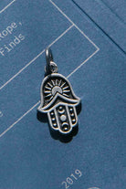 Silver Hamsa hand charm on a blue background