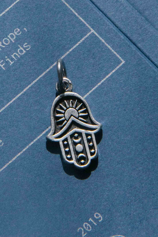 Silver Hamsa hand charm on a blue background