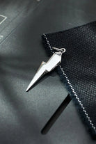 Silver lightning bolt pendant on a black textured surface
