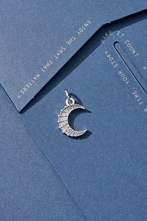 Silver crescent moon pendant on a blue card with motivational text