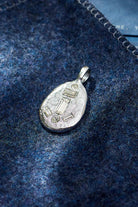 Silver pendant on a blue textured fabric background