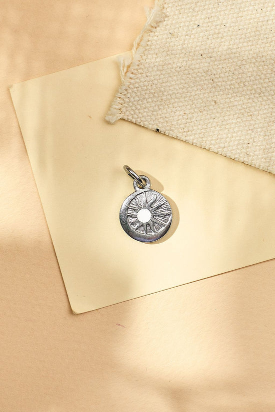 Silver pendant on a beige fabric background