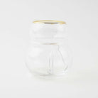 Empty snowman shaped clear drinking glass with a gold rim on a white background