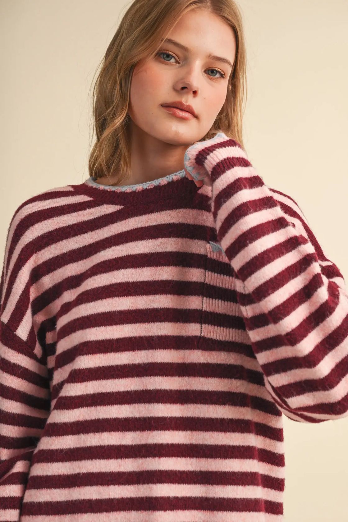 Woman wearing the &merci Striped Pocket Sweater in wine and pink stripes with a crewneck and chest pocket, front view