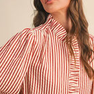 Close-up of the &merci Striped Ruffle Blouse showing the ruffled high neckline and ruffle-trimmed button placket
