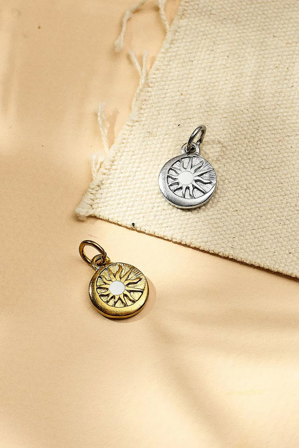 Two sun-shaped pendants on a beige fabric background
