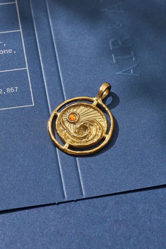 Gold pendant with a circular design on a blue surface
