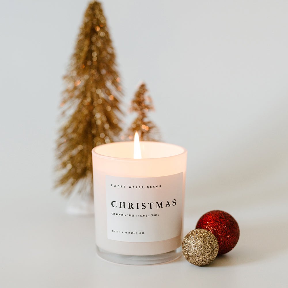 Lit Sweet Water Decor Christmas soy candle styled with a gold bottle-brush tree