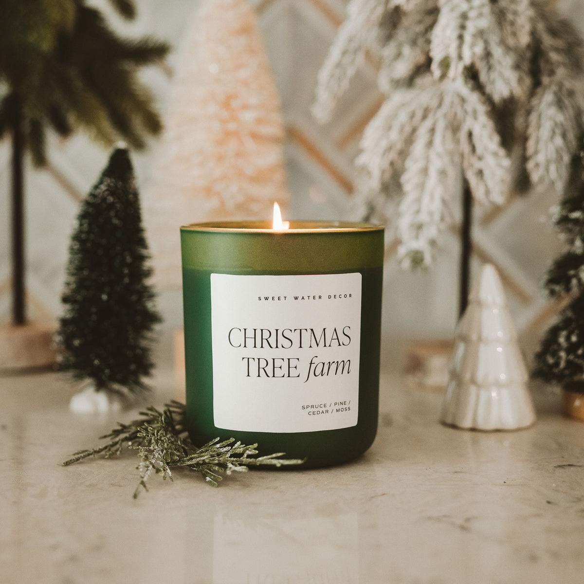Christmas Tree Farm 15 oz soy candle in a green matte jar styled with mini trees