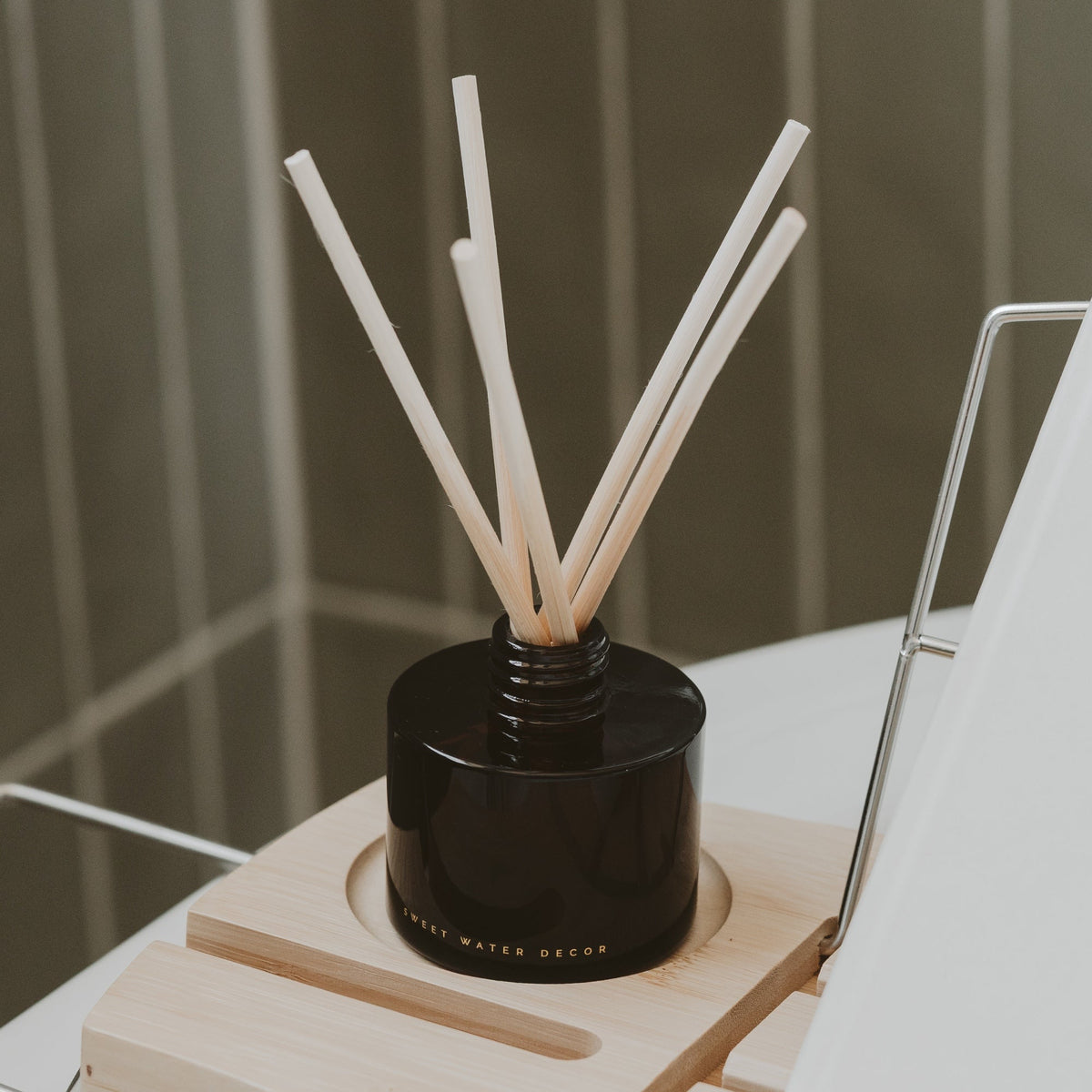 Sweet Water Decor amber glass reed diffuser with natural reeds styled on a table