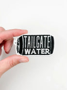 Hand holding a 'Tailgate Water' patch against a white background