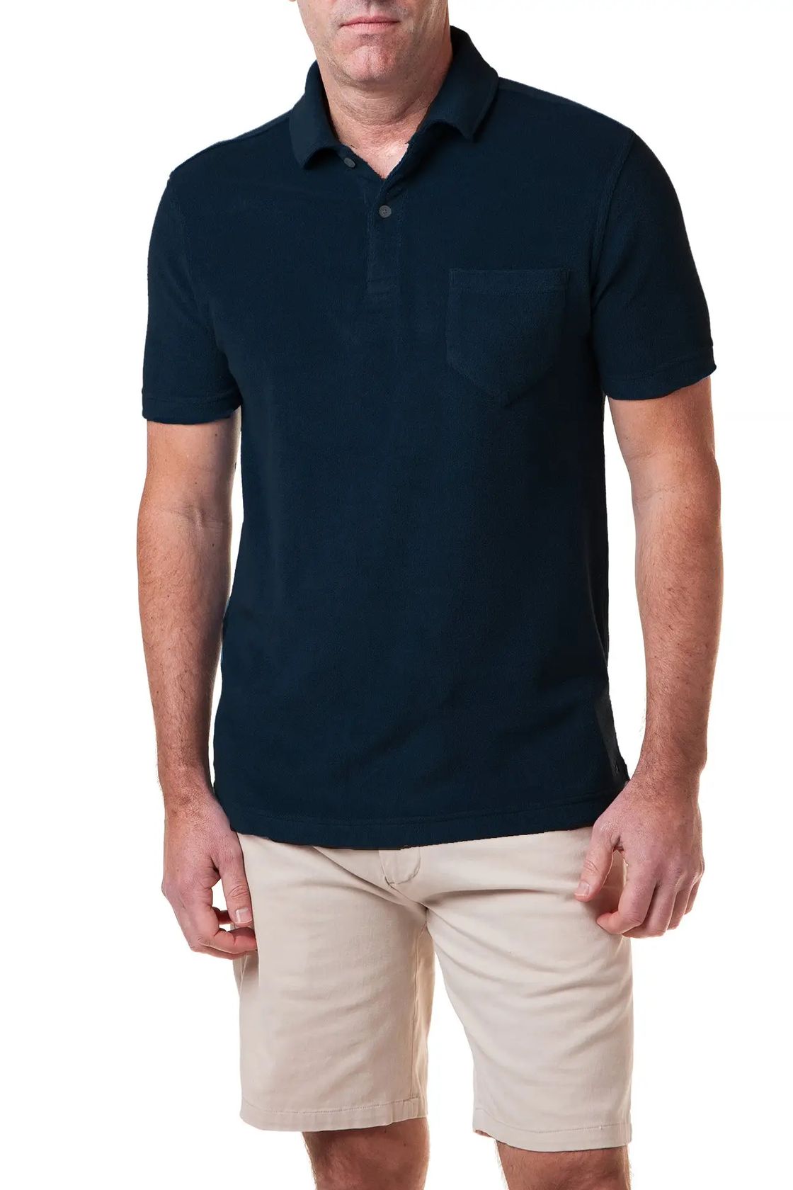 Man wearing a navy blue polo shirt and beige shorts on a white background