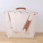 Beige tote bag with brown leather accents on a wooden surface