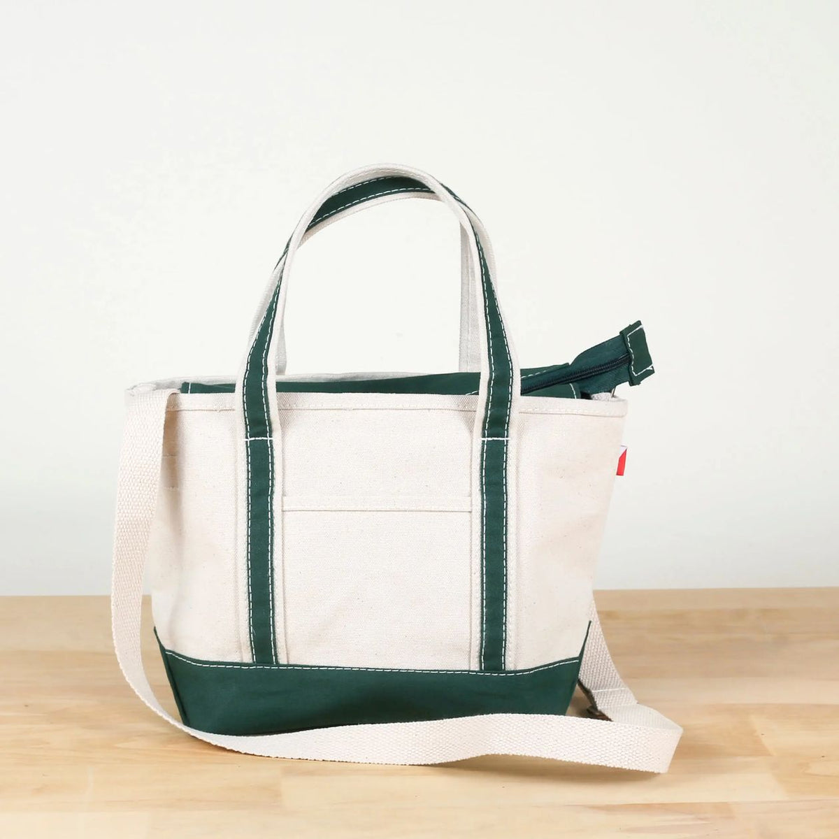 White tote bag with green accents on a wooden surface