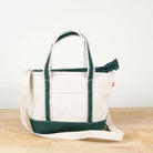 White tote bag with green accents on a wooden surface