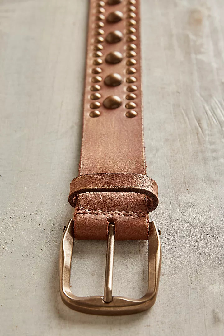 Close-up of cognac leather belt with rounded studs and antiqued brass-tone buckle