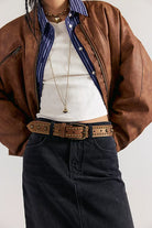 We The Free Sola Stud Belt in cognac leather worn at the waist over dark denim with a brown leather jacket