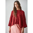 Wine red cable-knit cotton pullover sweater with a boxy cropped fit and three-quarter sleeves, worn with a pink satin skirt